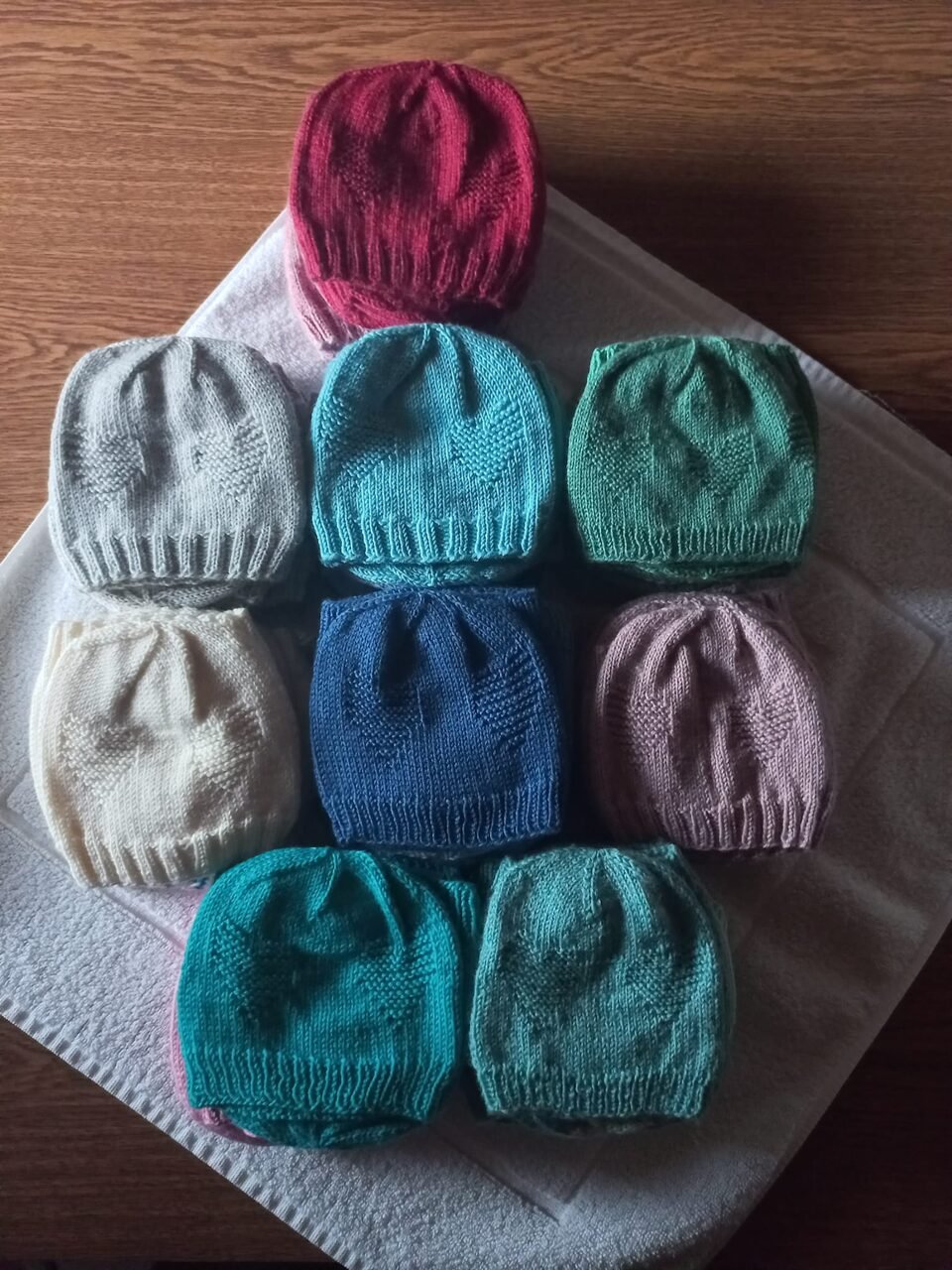 Neun handgestrickte Babymützen in verschiedenen Farben